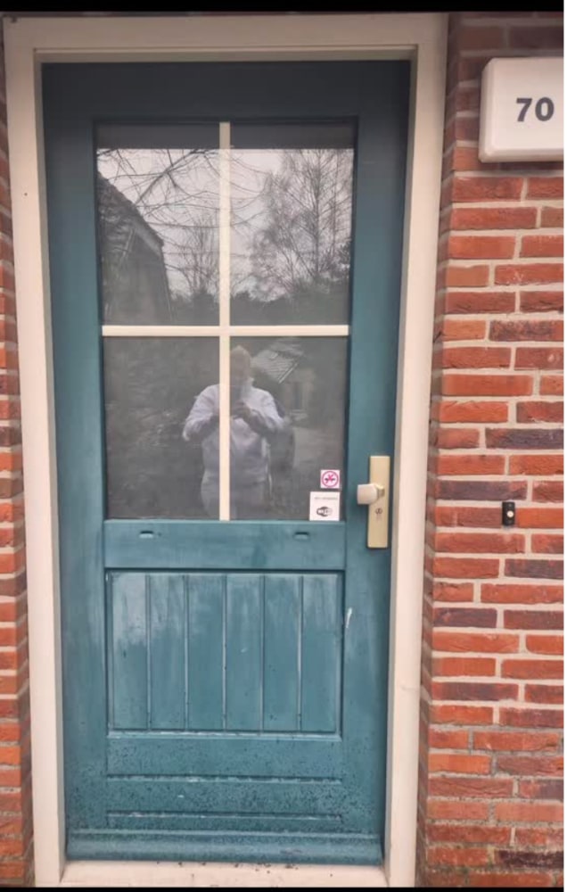 Donkergroene houten achterdeur met wit kozijn in een rode bakstenen gevel